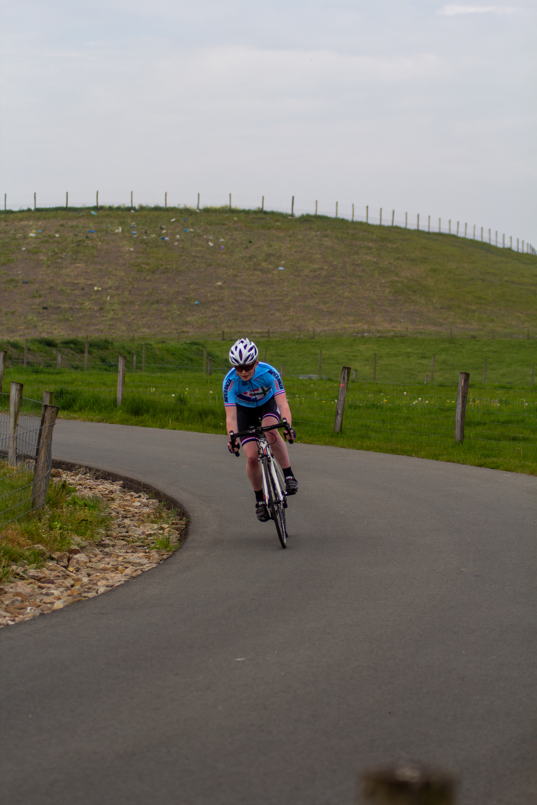 A cyclist with the number 6 on her bike is riding down a road.