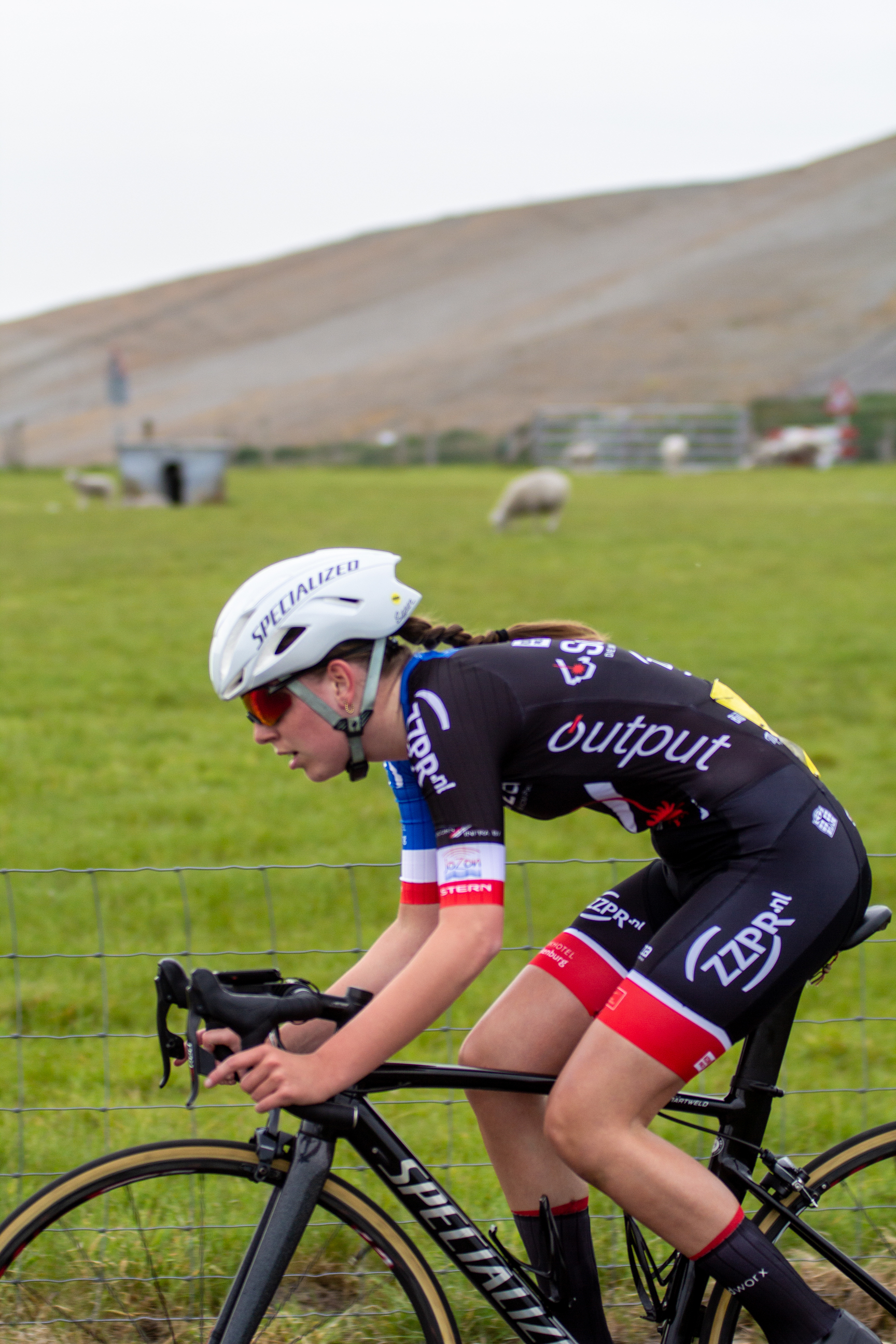 A person wearing a blue and white helmet is riding a bicycle with the words "Output" on their uniform.