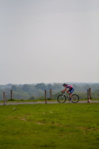 A cyclist is riding a bike on a field near some poles.