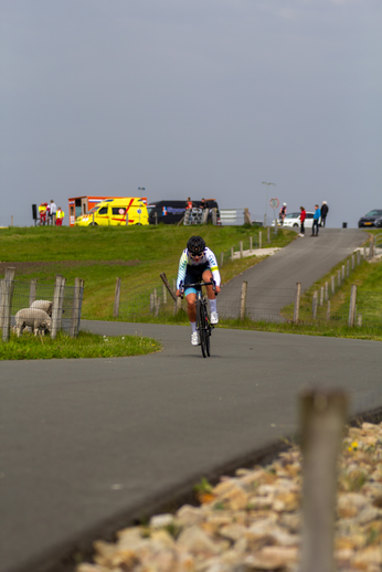 A man in a blue and white shirt is riding a bike down the road.