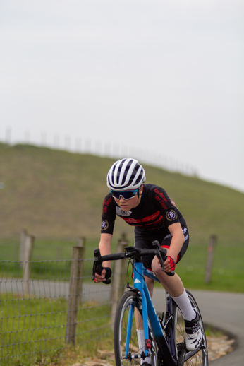 A young woman in a black and red jersey riding a blue bicycle.