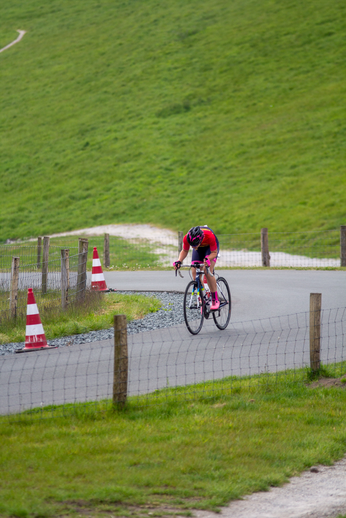 A cyclist on a road near some orange and white cones.