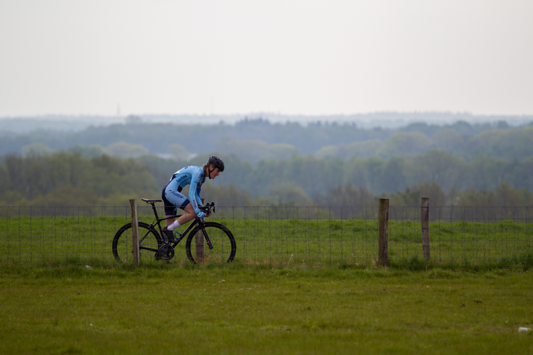 A cyclist in a blue shirt and helmet is riding on a field of grass.