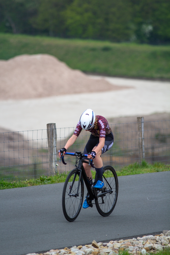 A cyclist is wearing a white and blue helmet while riding her black bicycle.