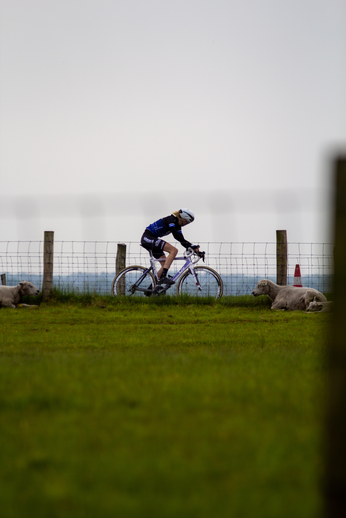 A female cyclist wears a blue helmet as she races her bike through the countryside.