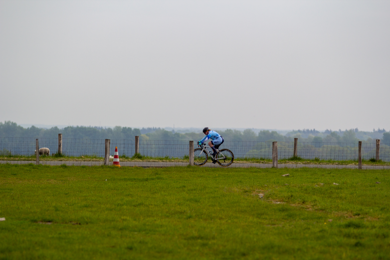 A person is riding a bike around cones in a grassy field.