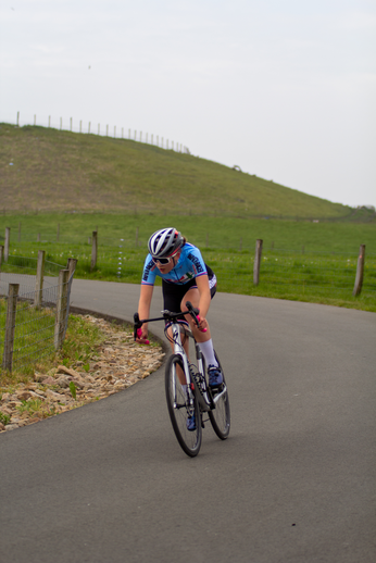 A lady on a bike with the numbers 1 and 4 on her shoulders, wearing a blue and white outfit.