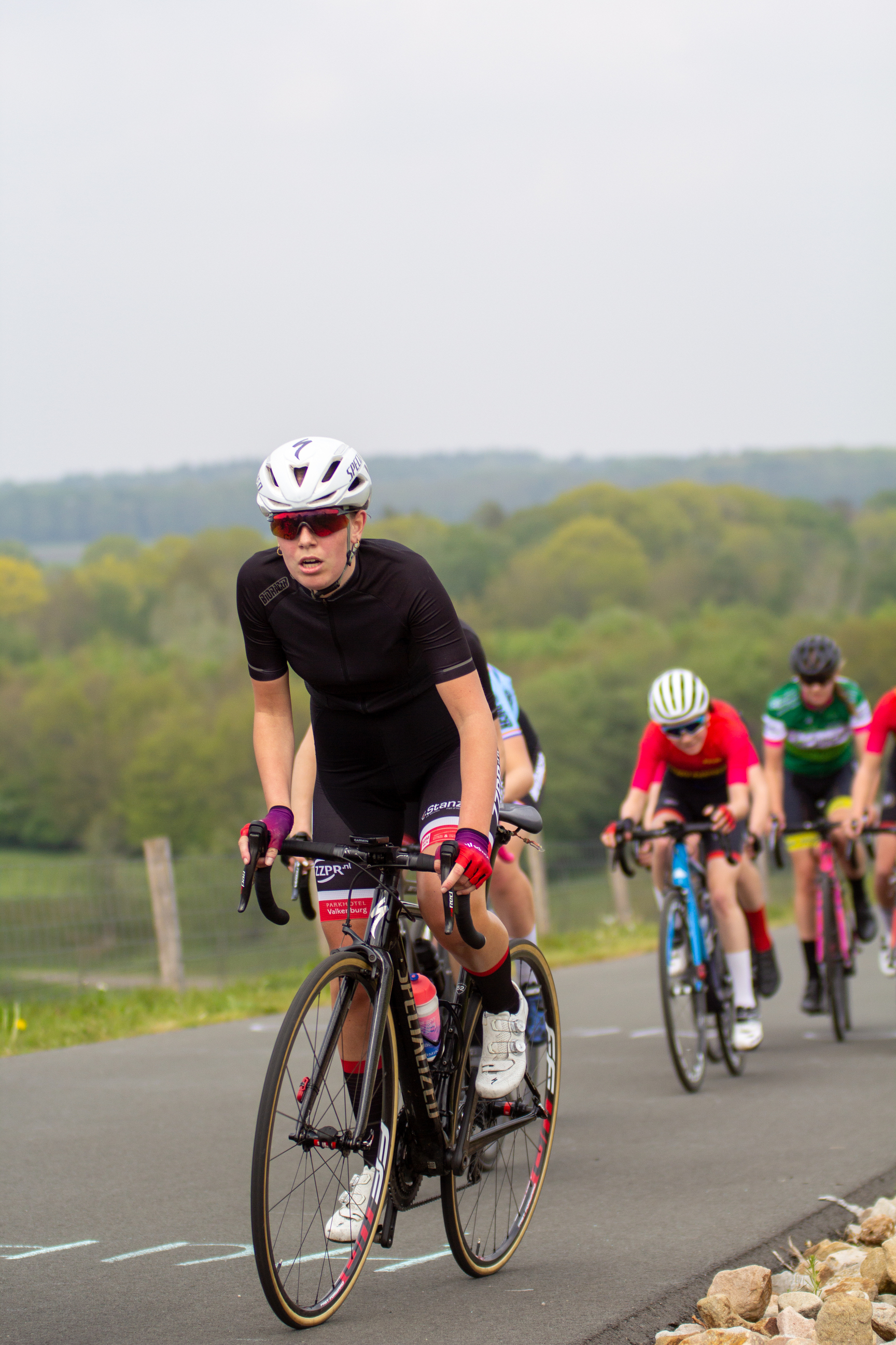 A female cyclist on a road in the Daams Criterium race.