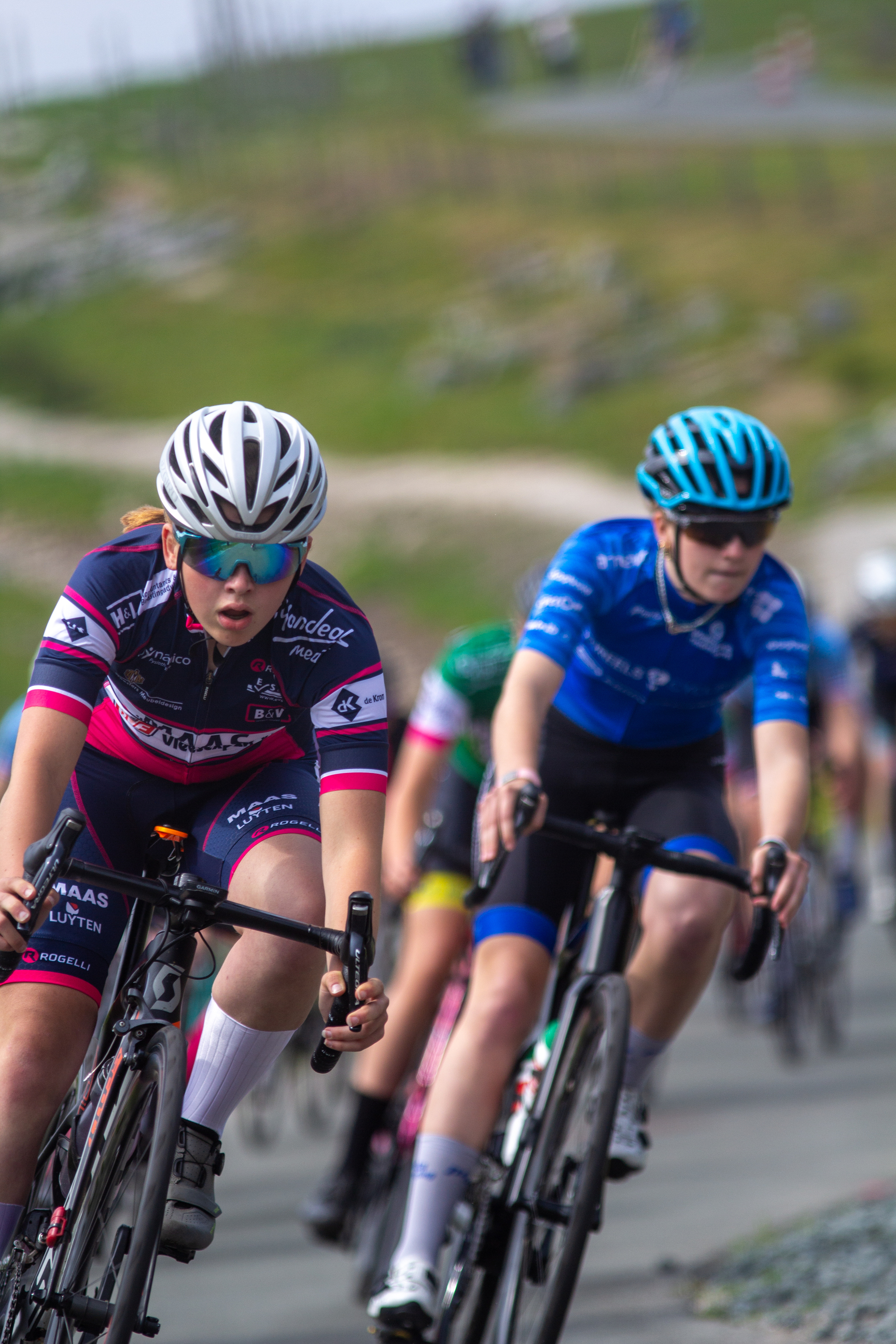 Two young female athletes on their bikes, racing each other in the Dames Criterium race.