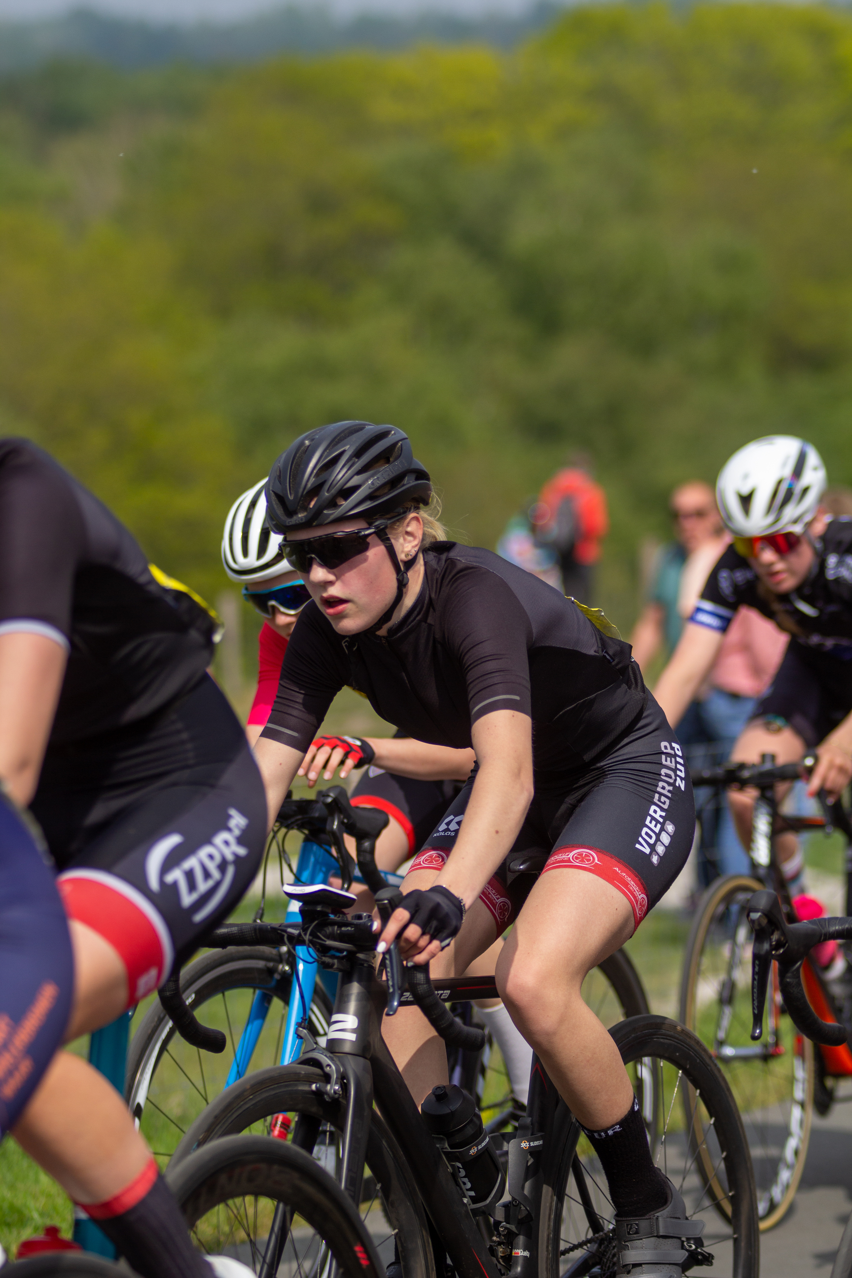 Women racing bikes with number 12, 3 and 2 in the back.