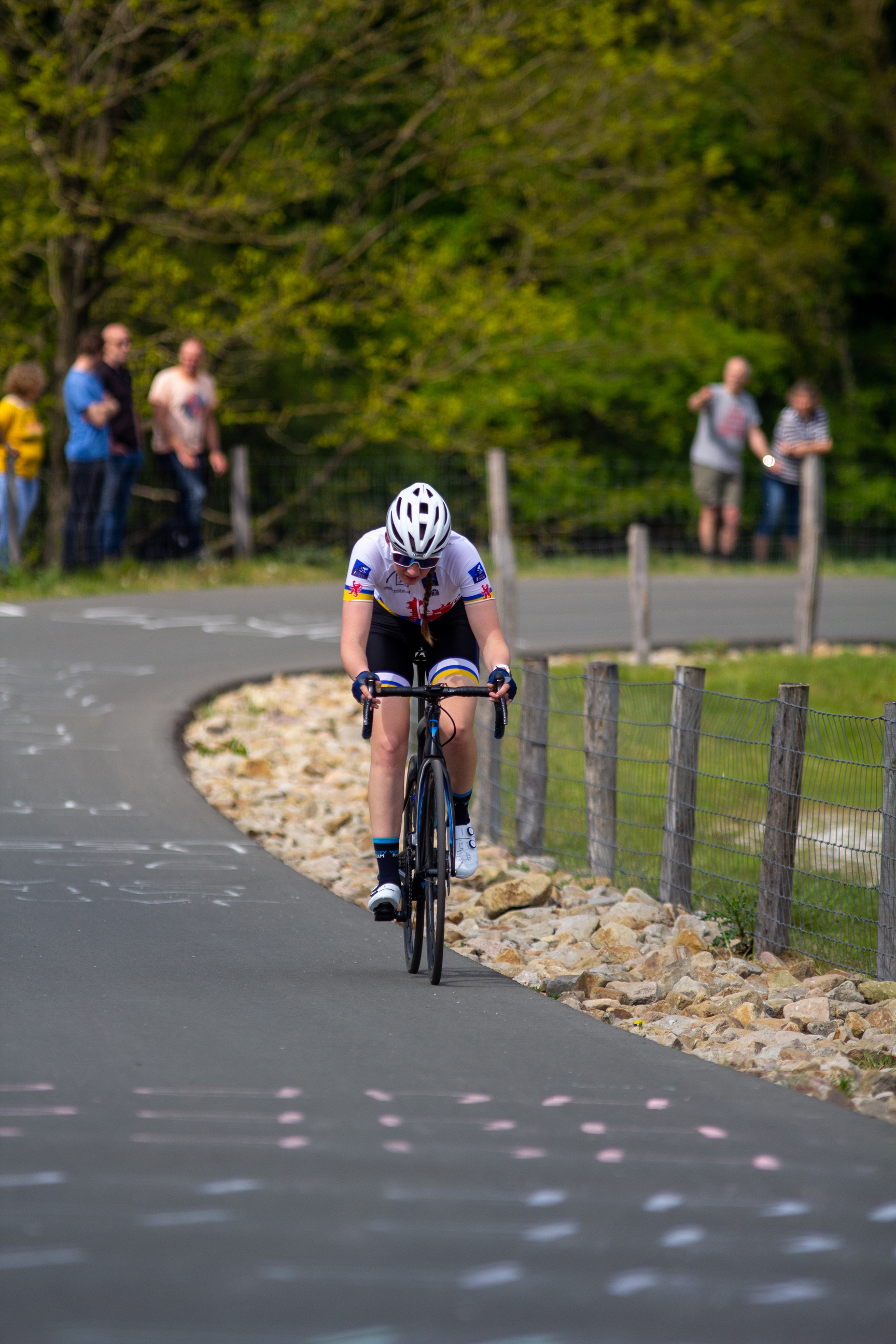 A female cyclist wearing a white helmet and riding a bicycle.