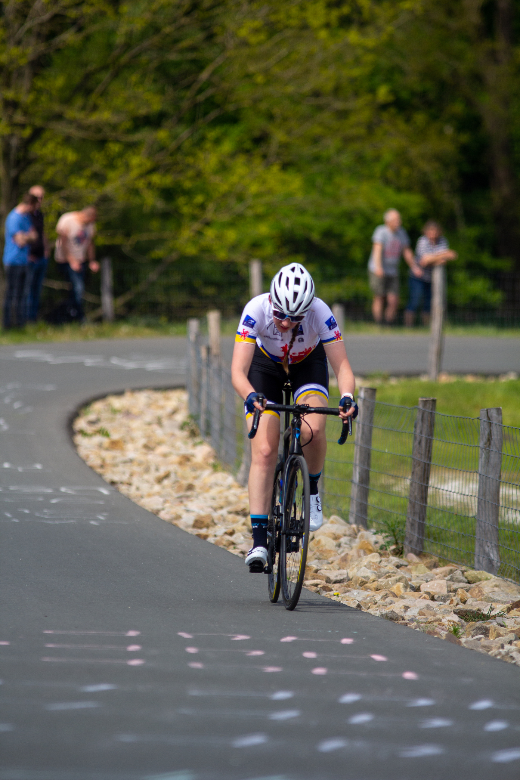 A woman on a bike wearing a white helmet with "Dames" written on it.