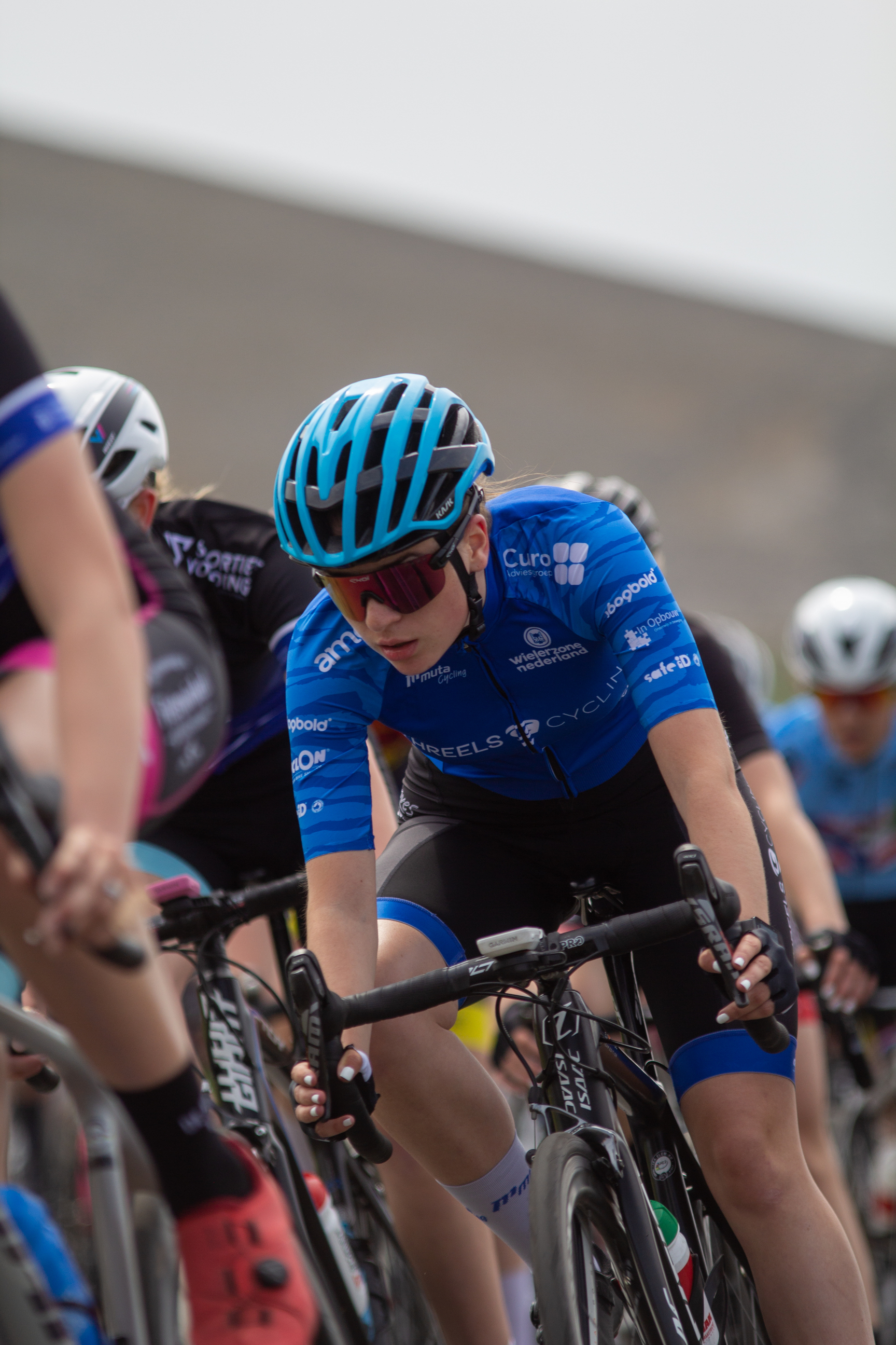 A group of female cyclists race down a road in the 2022 Tweedaagse.