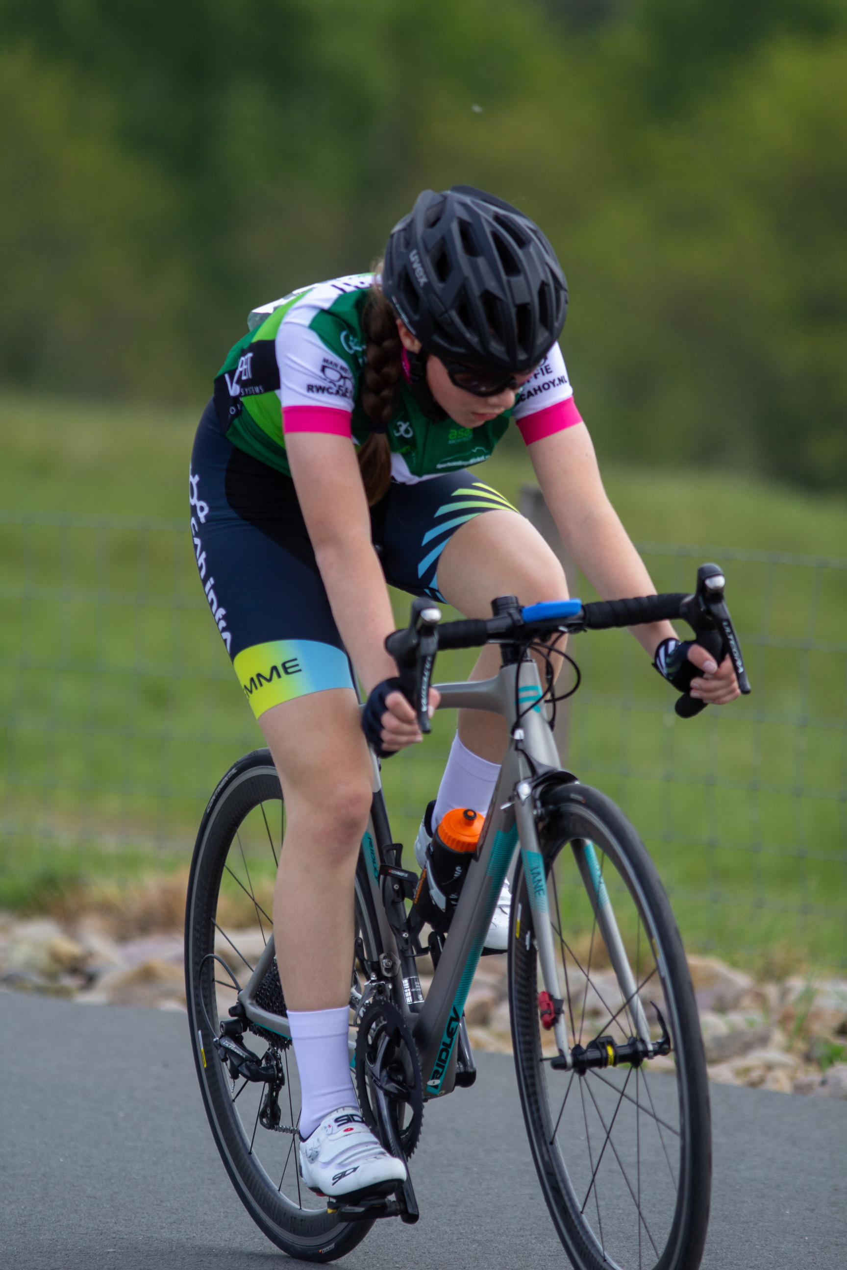 A woman in a purple jersey riding a bike on the road.