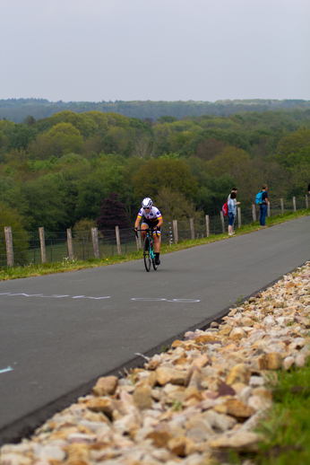 A cyclist racing down a hill with three other racers following her.