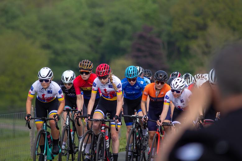 Six cyclists riding in a line down the road with different colored jerseys.