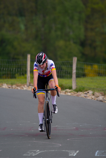 A woman in a white shirt and black shorts on her bicycle.