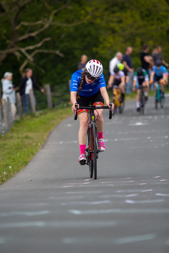 A girl is riding a bicycle with the words "dames criterium" written on her shirt.