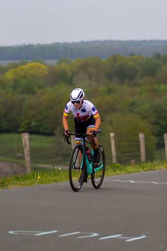 A cyclist is riding on a race course with the word "tweedaagse" in blue on the road.