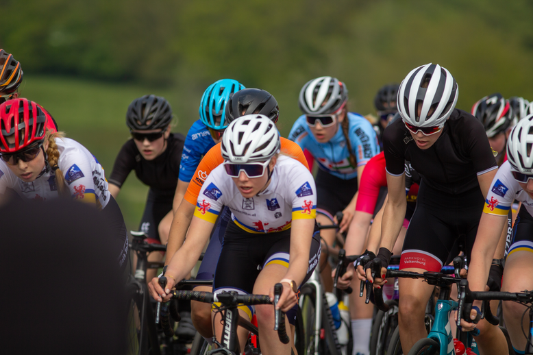 Eight women wearing helmets are riding bikes in a group.