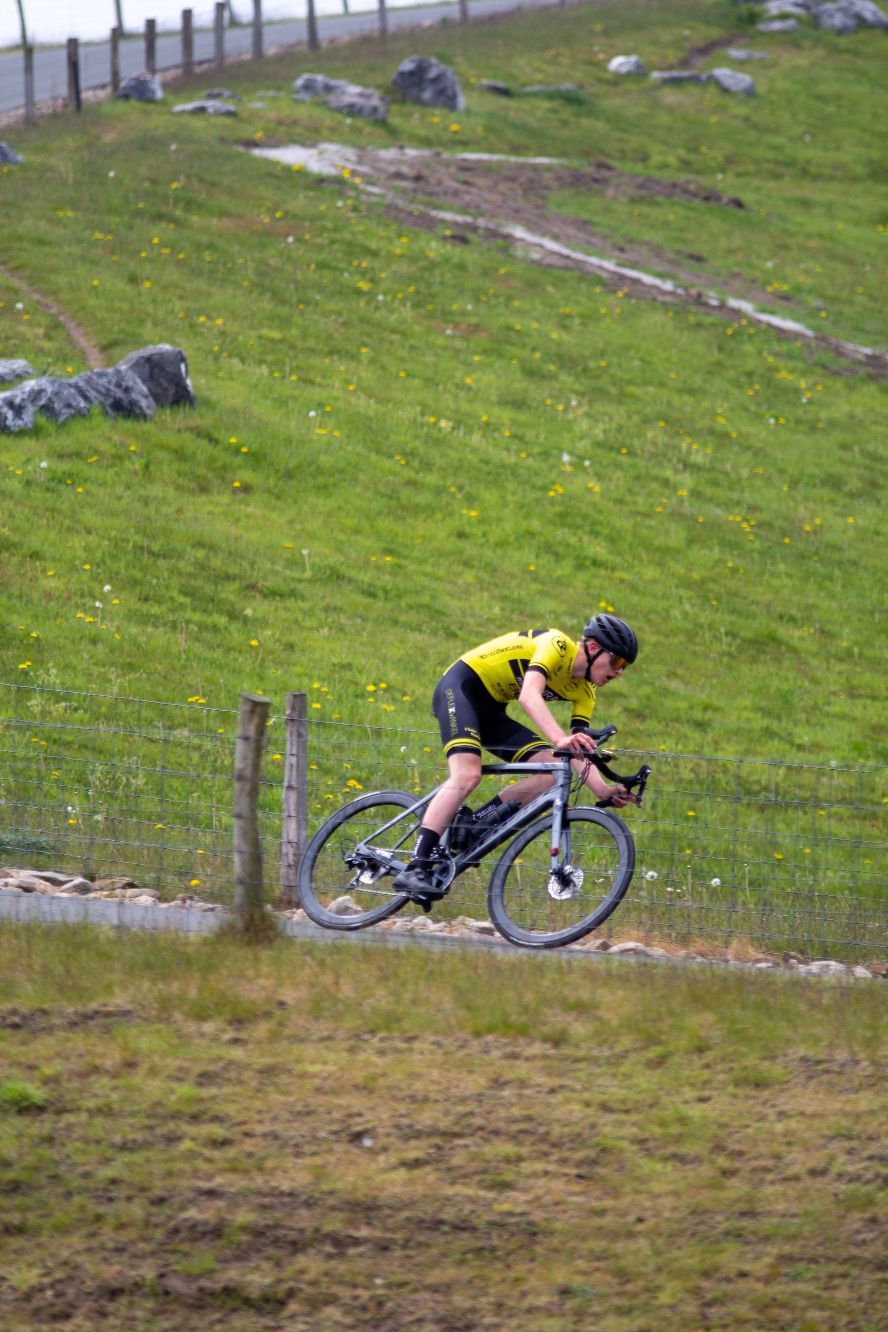 A man is riding a bike in the grassy field at the Coll du Vam Tweedaagse.