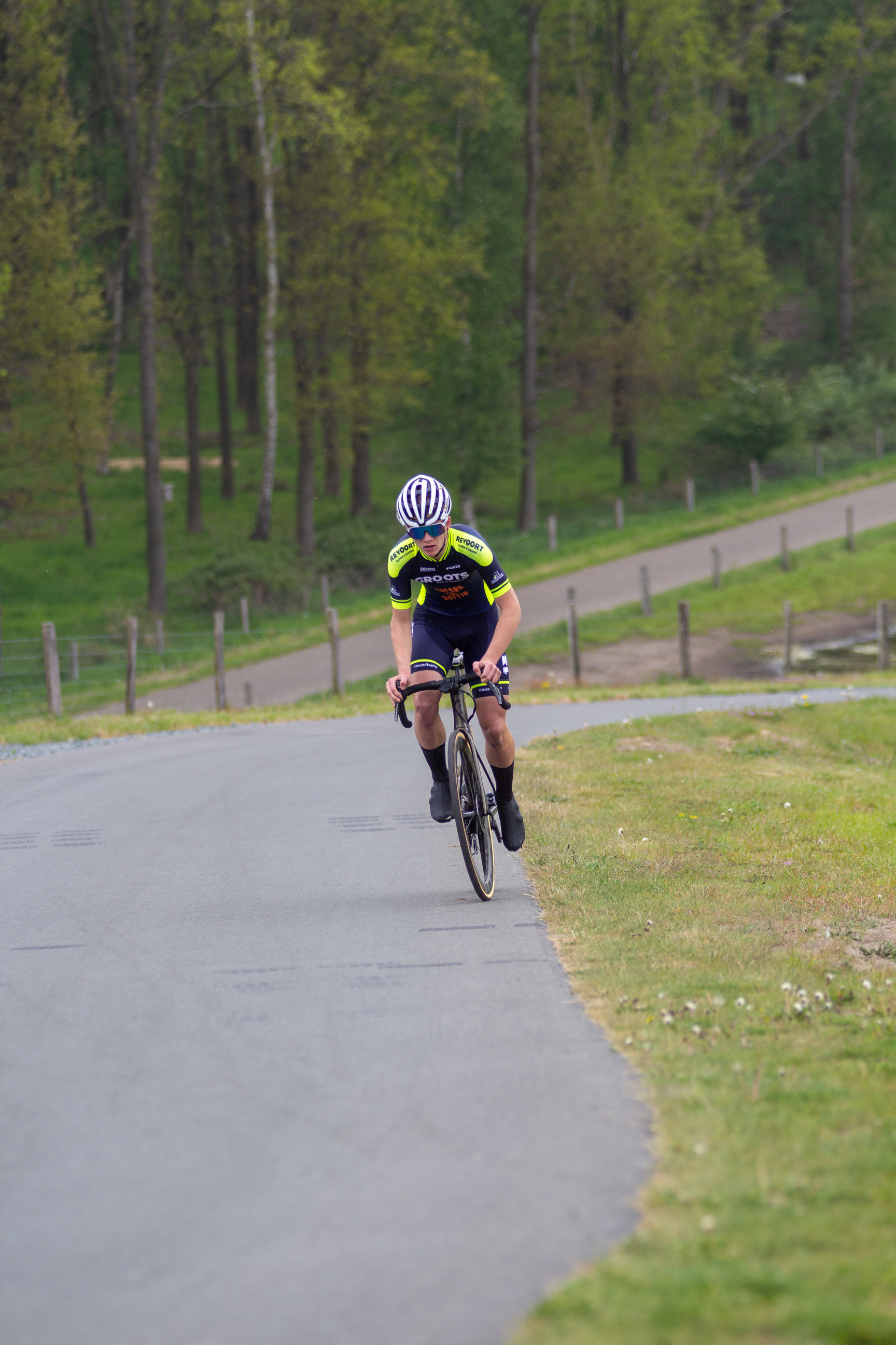 A man in a cycling race wears a black helmet with a logo.