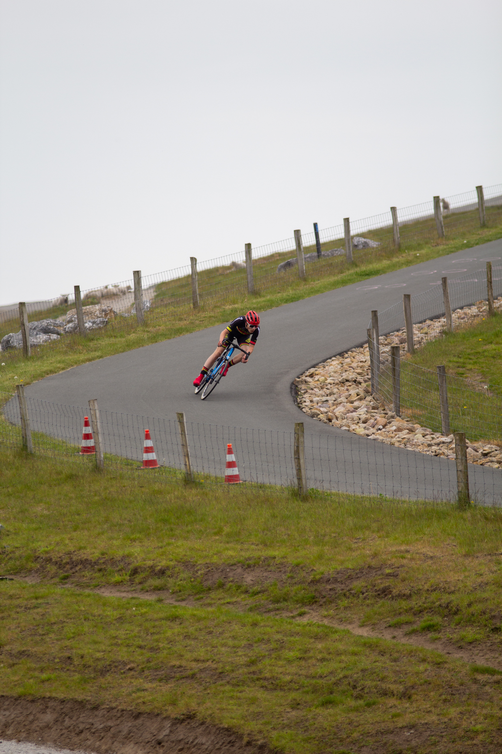 A cyclist is racing through a course that is marked by orange and white cones.