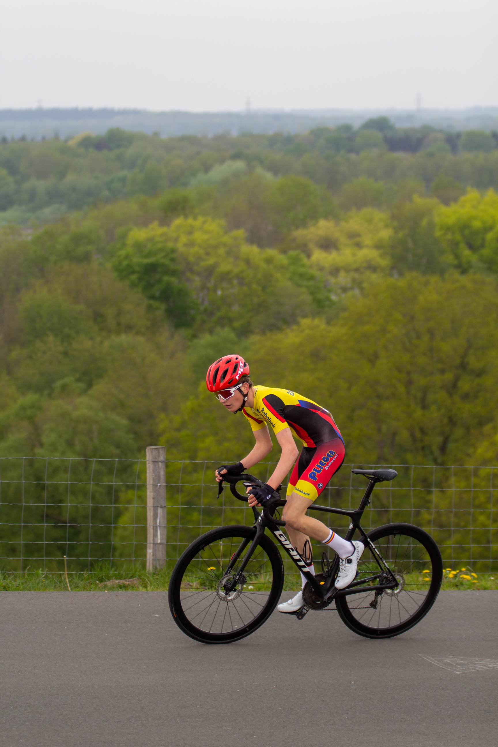 A person wearing a red and yellow cycling outfit is riding a bike.