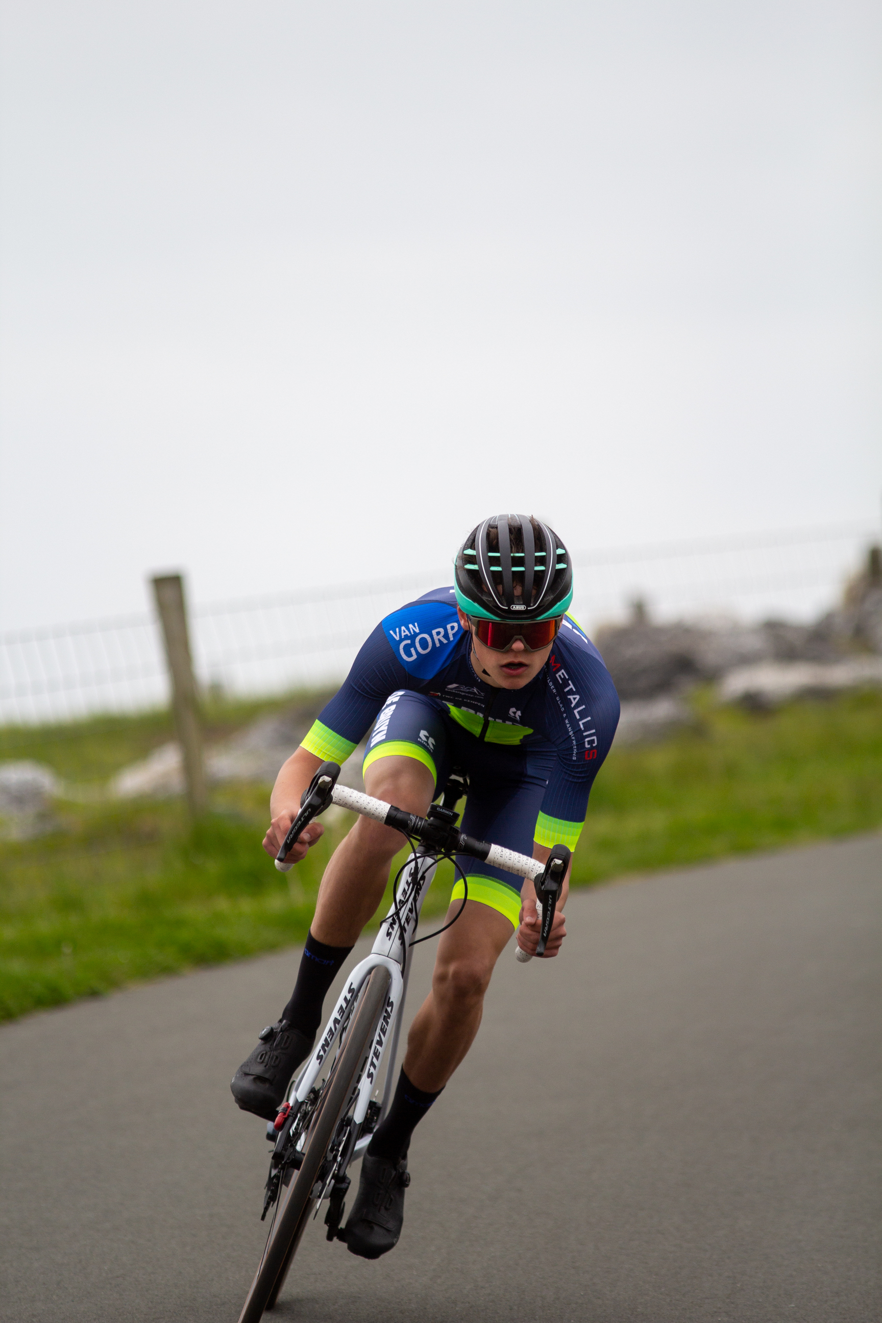 A man in a blue jersey and black helmet races on a bike.