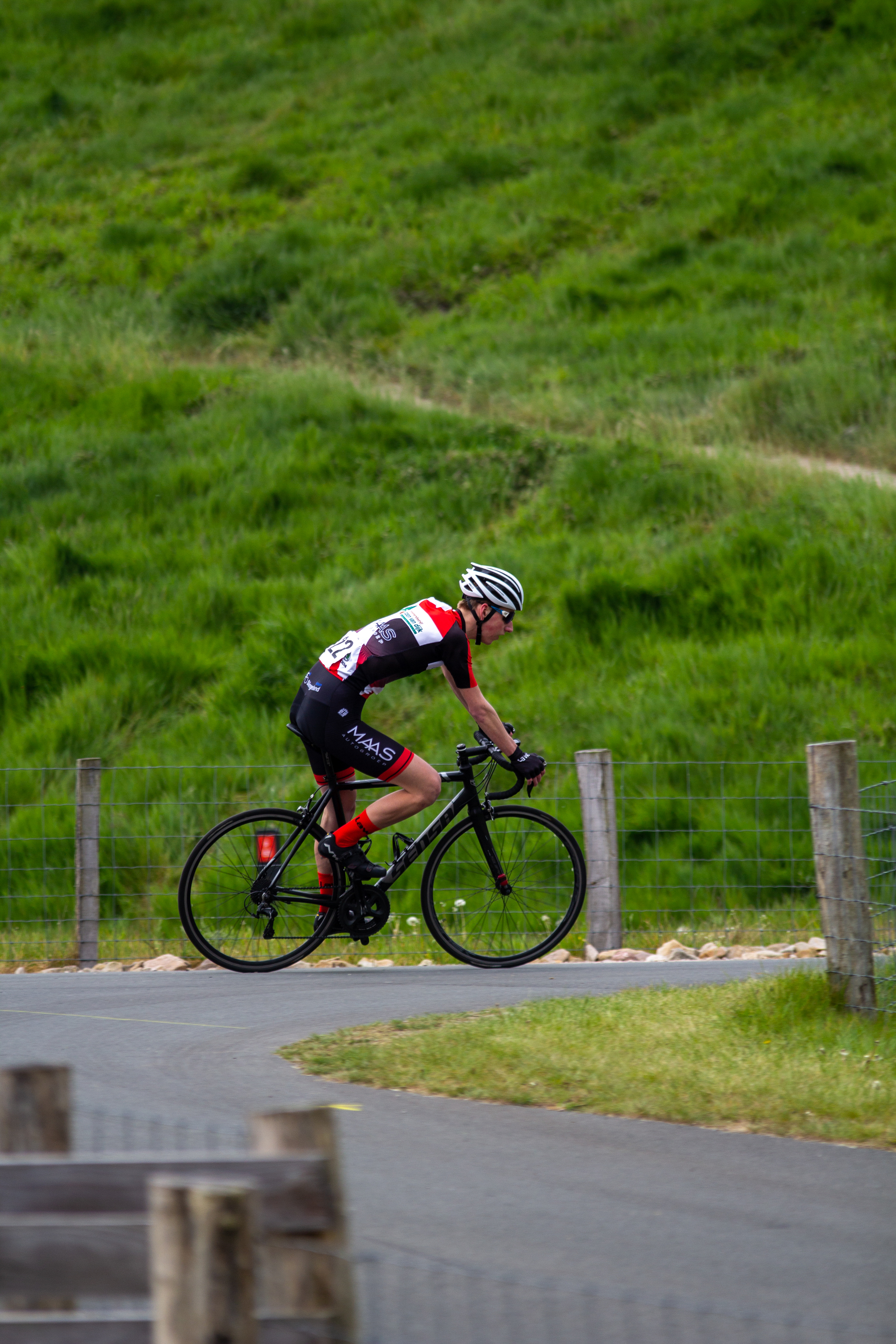 A man riding a bicycle on the side of a road, wearing black and red.