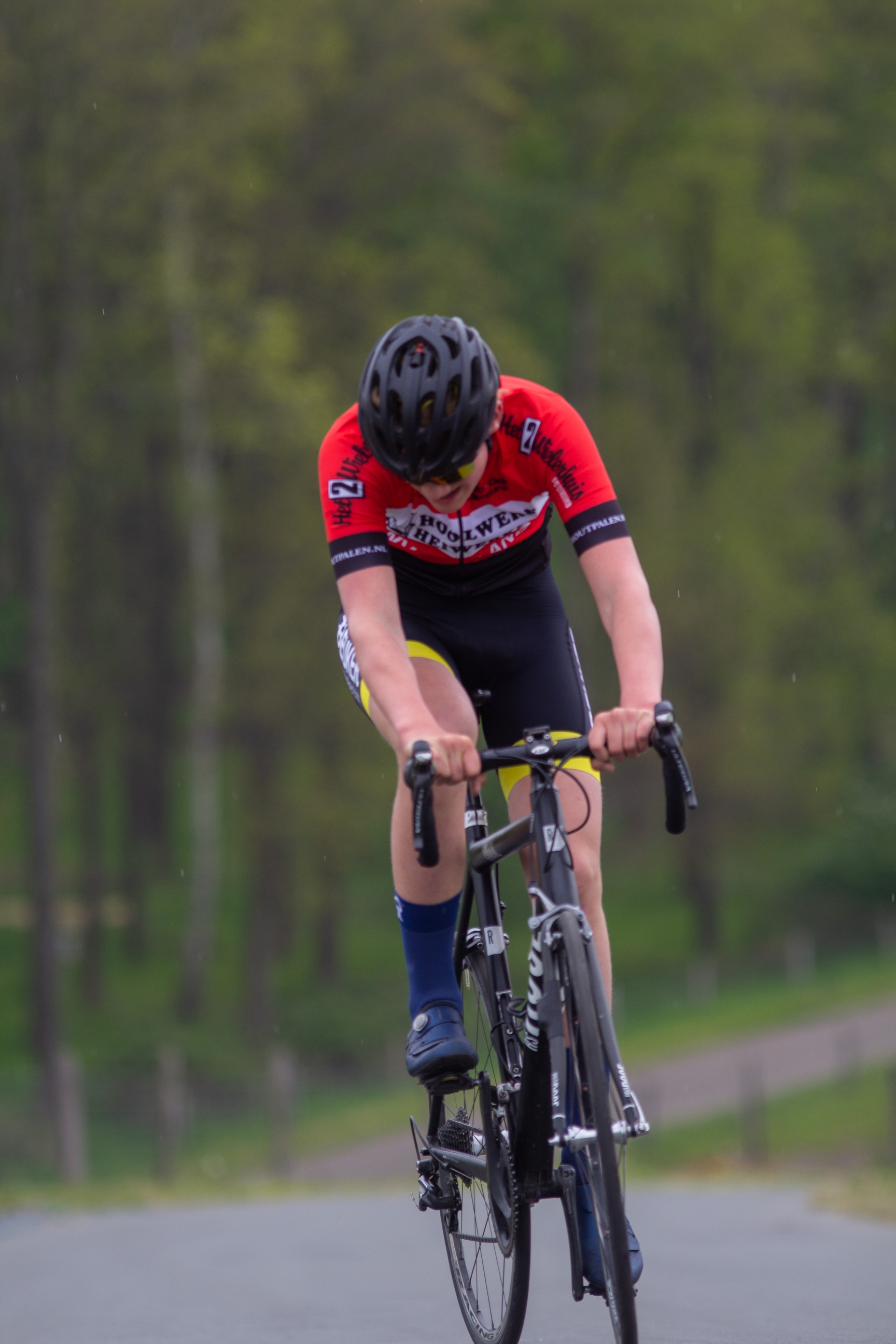 A man rides a bike with yellow shorts and blue socks.