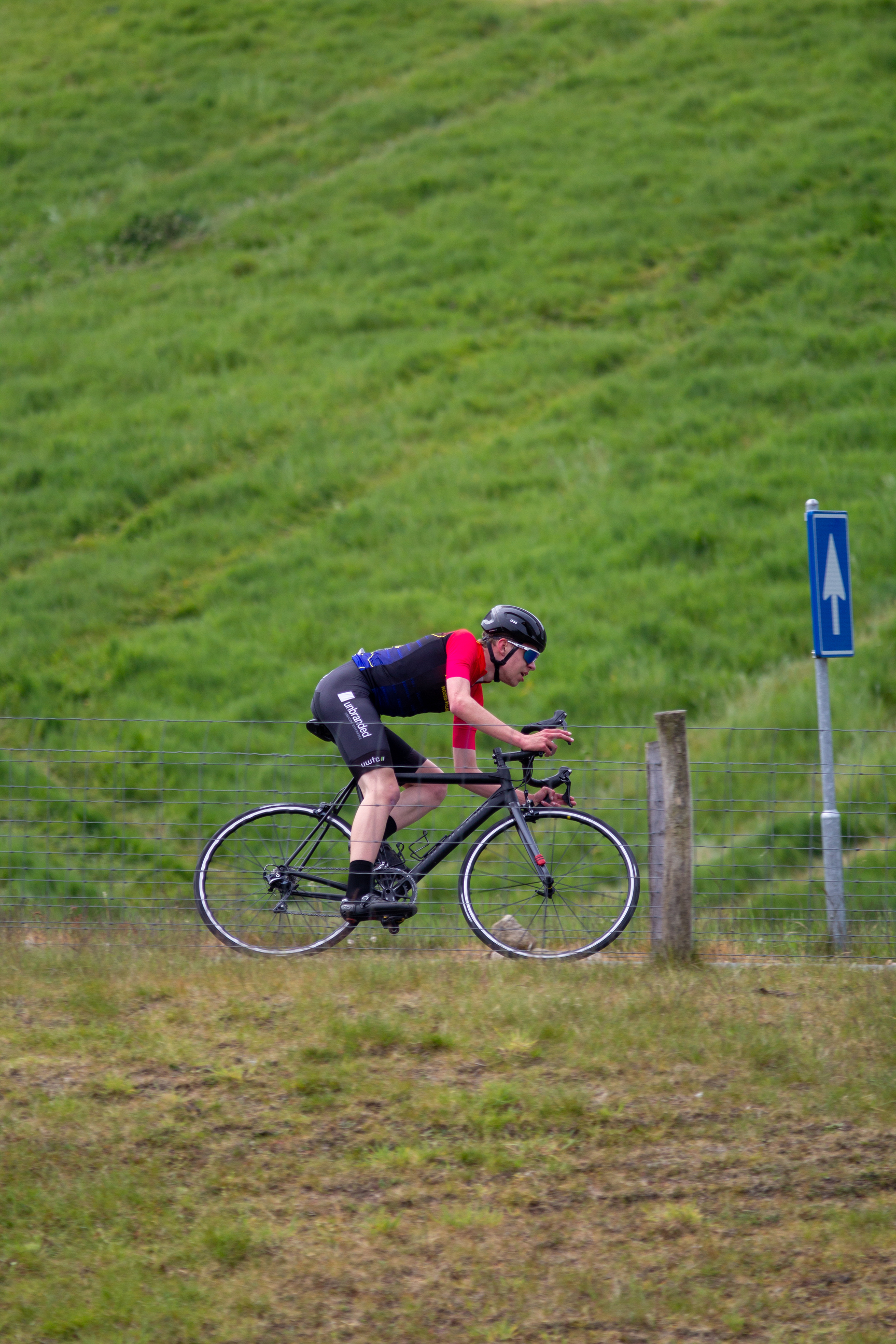 A man is riding a bicycle near a sign for cyclists.