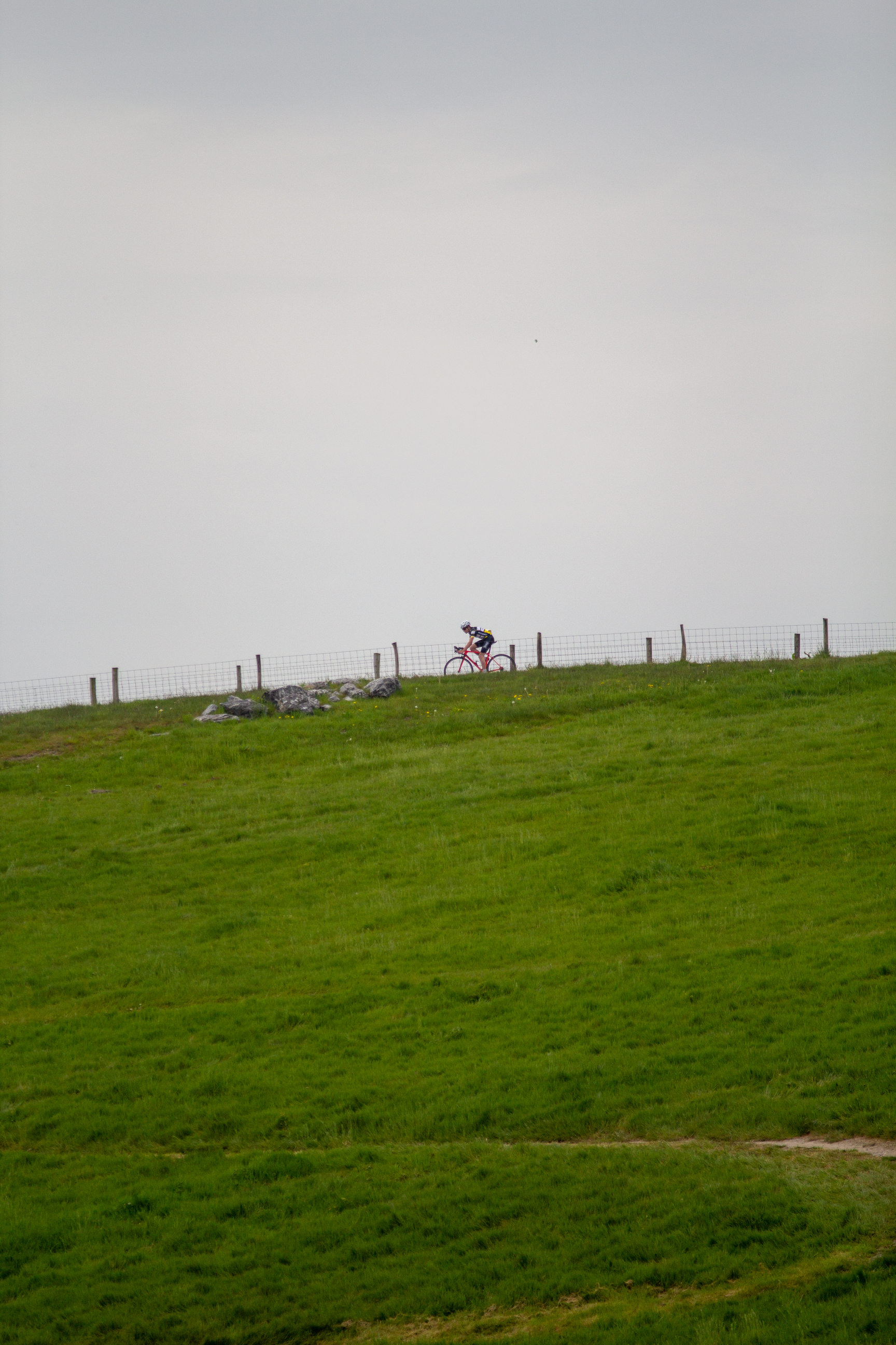 A man on a bicycle is riding past the Heren TT sign.