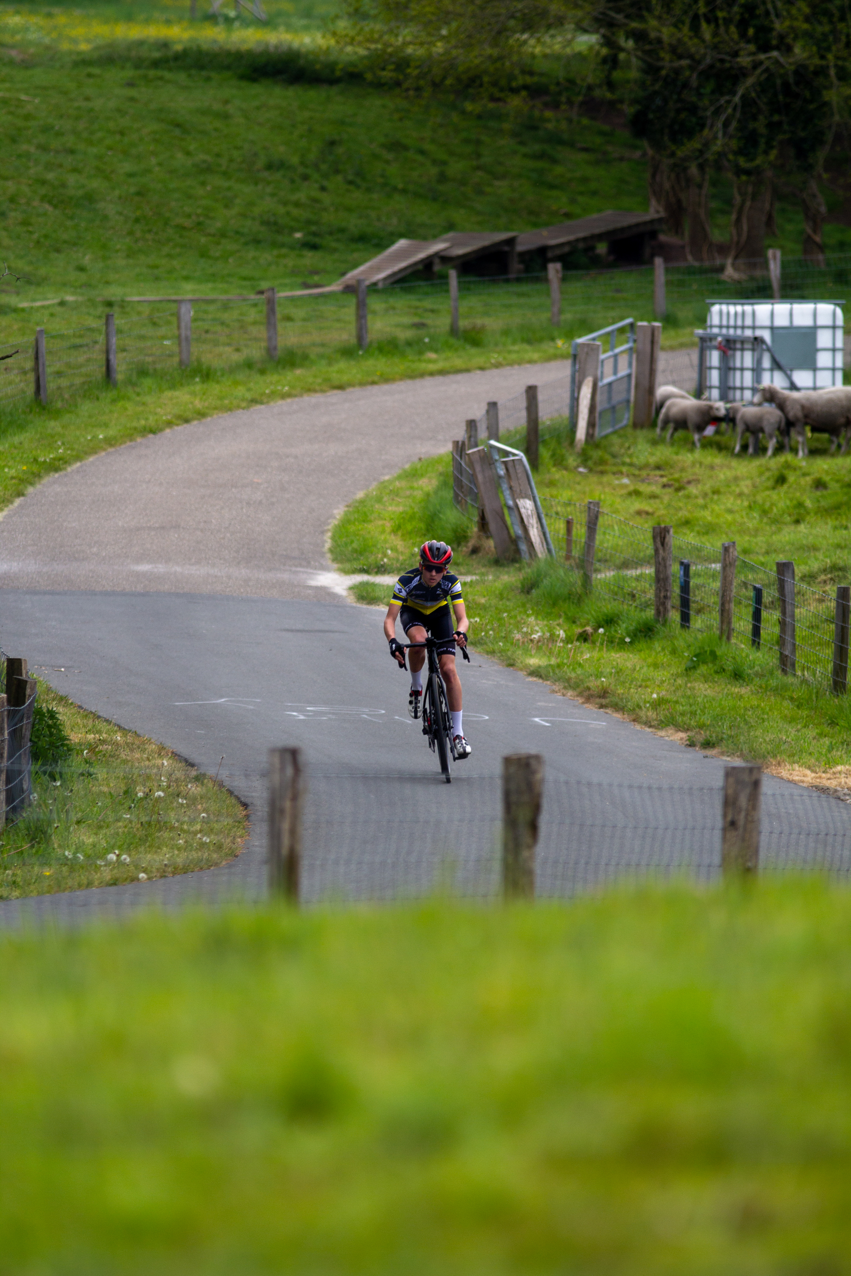 A man wearing a red helmet rides his bike on a road.