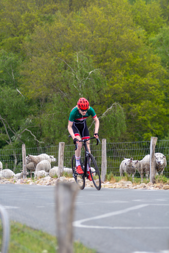 A cyclist wearing a red helmet and riding a black bicycle with a red frame.