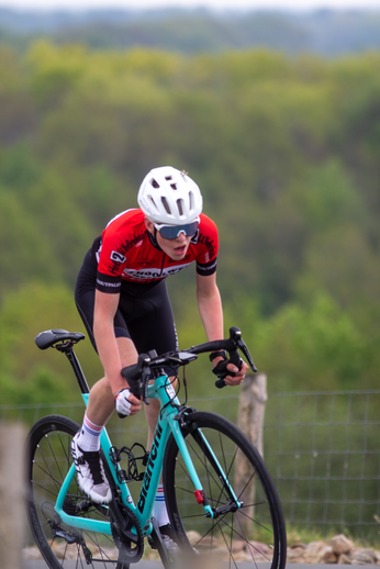 Man wearing a red and black shirt riding a blue bicycle.