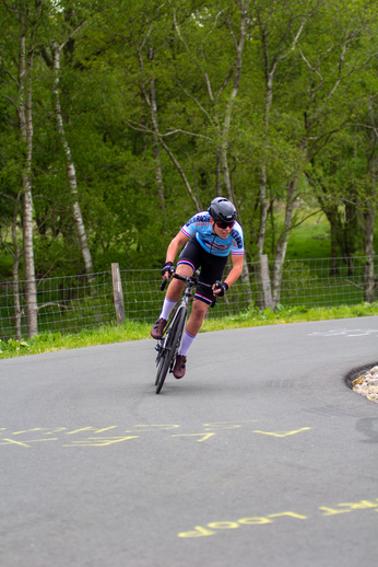 A person riding a bicycle wearing blue, pink and purple.