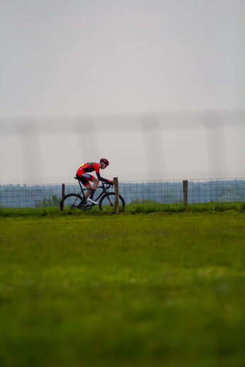 A man on a bike in an open field wearing a red helmet with the number 14 on his back.