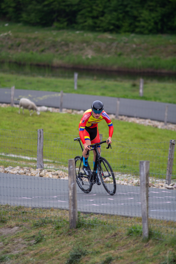 A cyclist wearing a red, yellow and blue jersey riding a black bike.