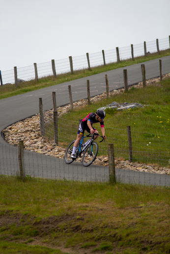 A man in a red jersey is riding his bike up a hill.