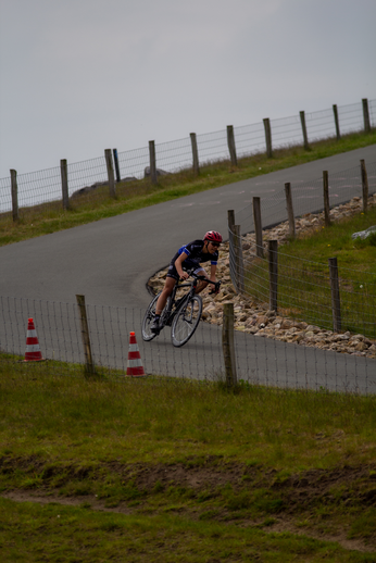 A person riding a bicycle on the road, wearing a red and blue helmet.