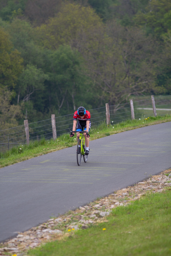 A cyclist in a red shirt is riding down a road with green handlebars. The photo is from the Tweedaagse event in 2022.