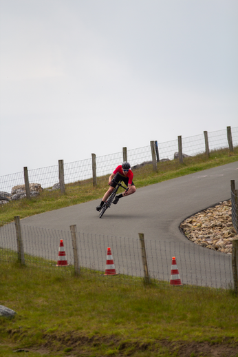 A cyclist racing down a hill with orange traffic cones lining the side of the road.