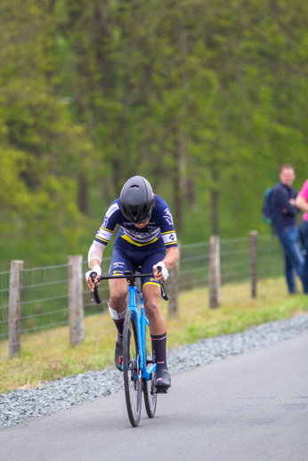 A person wearing a black and yellow jersey is riding a blue bike.