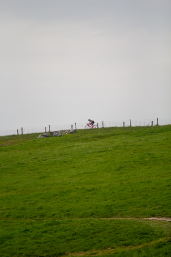 A man on a bicycle is riding past the Heren TT sign.