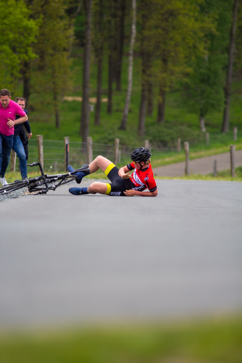 A woman wearing a red shirt and black shorts lies on the ground next to a bicycle.