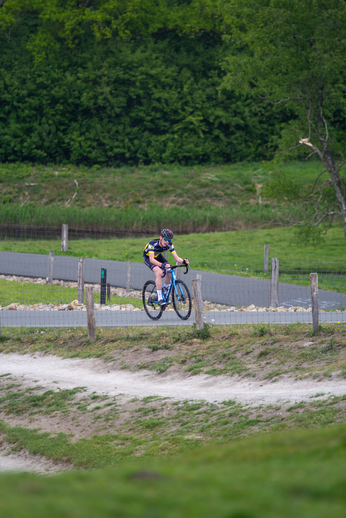 A cyclist rides through a forested area on his road bike.