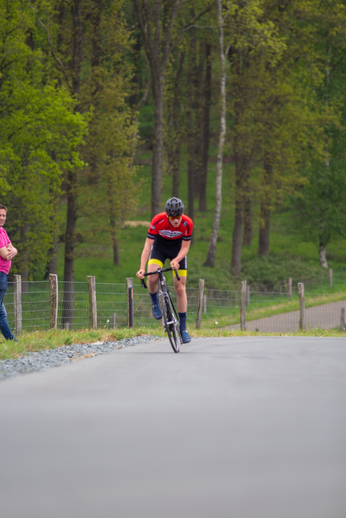 A man in a red and black jersey rides his bike down a hill.