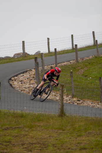 A man wearing a red helmet is riding a bike on the road.