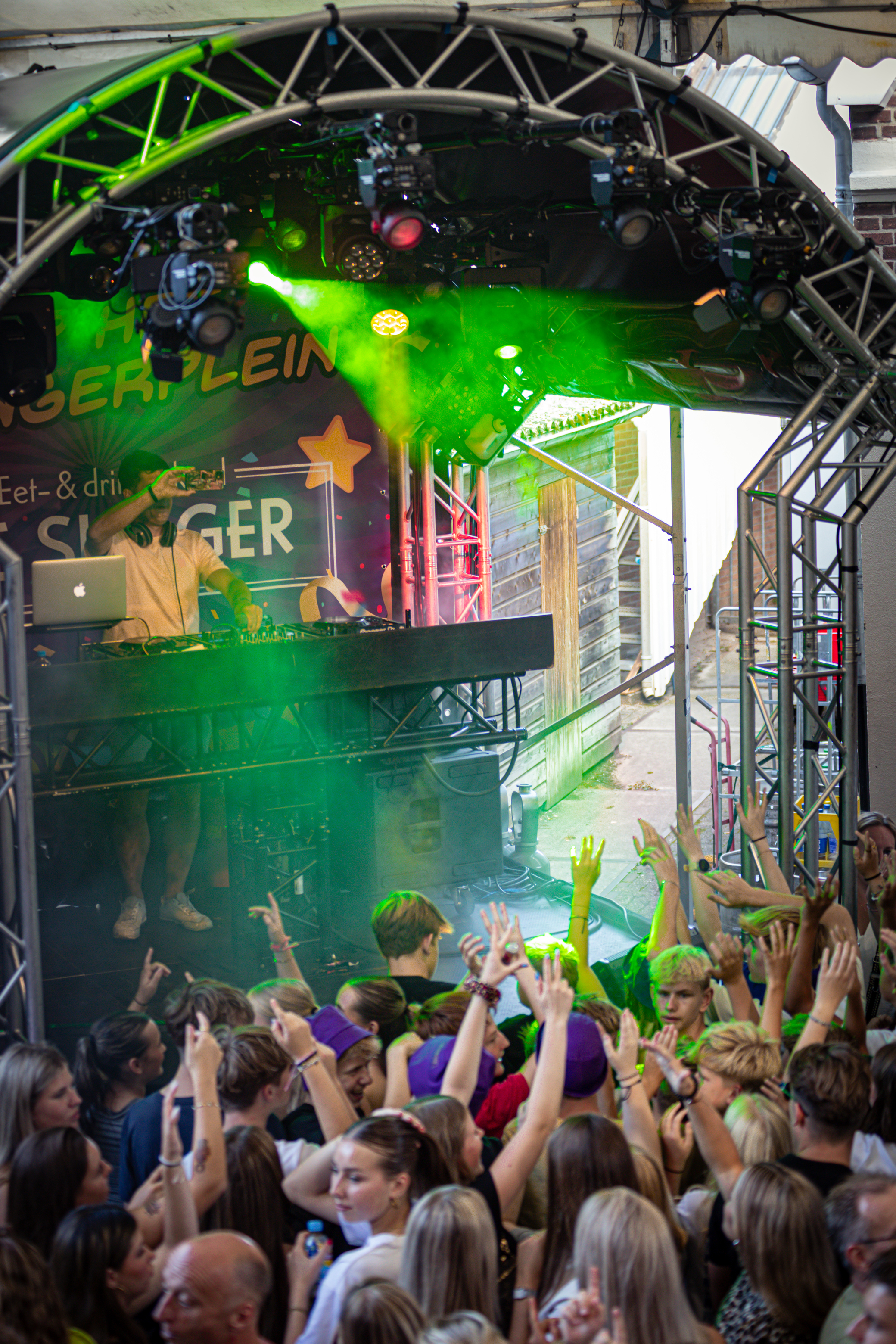 A crowd of people watch a DJ perform at the Slinger concert.